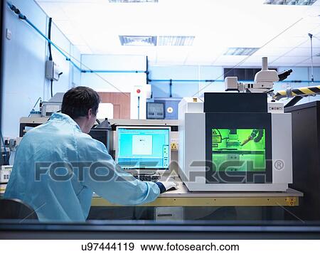 Stock Photo - Worker operating laser marking machine in clean room laboratory. Fotosearch