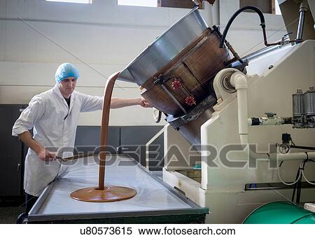 Stock Photography - Worker pouring confectionery fudge in chocolate factory. Fotosearch