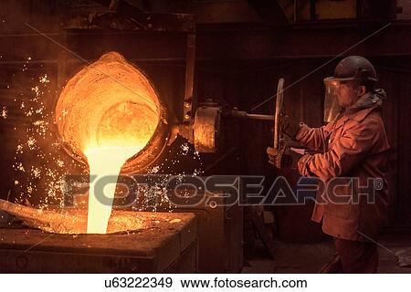 Stock Photo - Worker pouring molten metal from flask in foundry workshop. Fotosearch