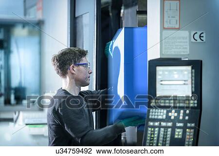 Stock Image -  Worker removing plastic part from injection moulding machine in plastics factory. Fotosearch