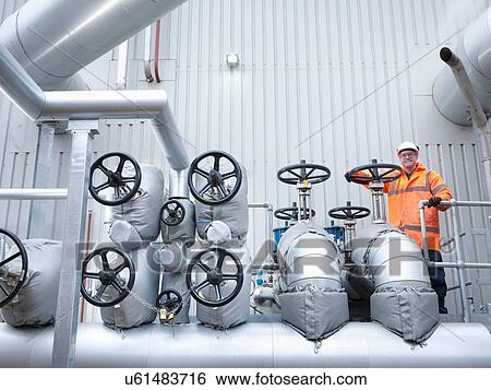 Stock Photograph - Worker standing by valves of gas fired power station. Fotosearch