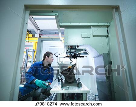 Picture - Worker using CNC machine in plastics factory. Fotosearch