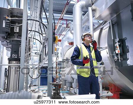 Stock Image - Worker using radio in gas fired power station. Fotosearch