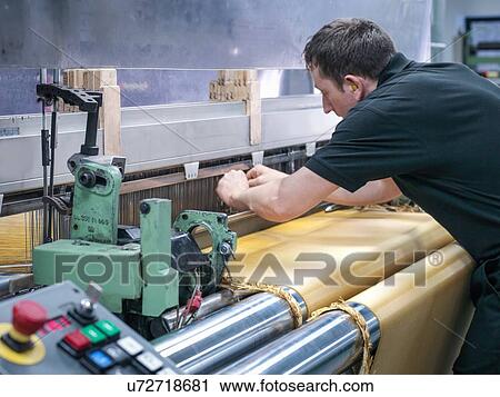 Stock Image - Worker weaving kevlar fabric in carbon fibre factory. Fotosearch