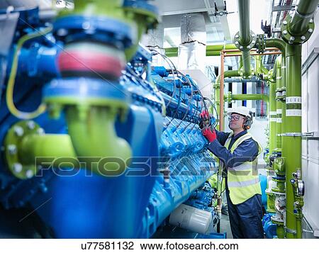 Stock Image - Worker with gas fired generator in gas fired power station. Fotosearch