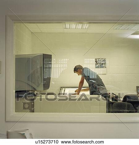 Stock Image - Worker with inspection box in printworks. Fotosearch