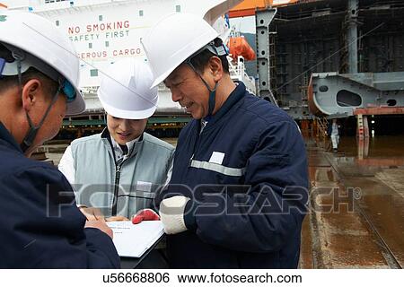 Stock Photograph - "Workers discussing plans at shipyard, GoSeong-gun, South Korea". Fotosearch