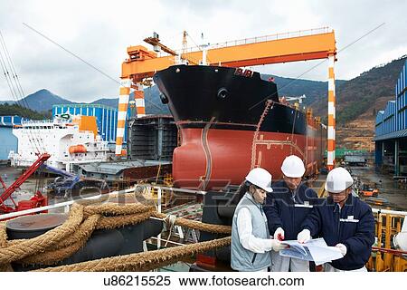Stock Photography - "Workers discussing plans at shipyard, GoSeong-gun, South Korea". Fotosearch