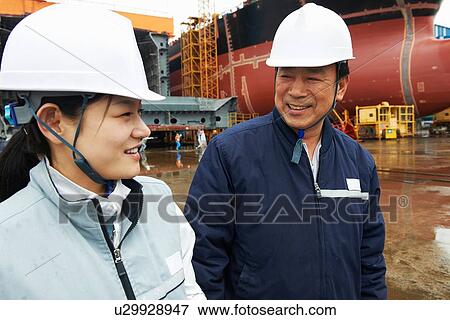 Stock Photo - "Workers having discussion at shipyard, GoSeong-gun, South Korea". Fotosearch