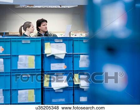 Stock Photo - Workers in discussion in automotive parts factory. Fotosearch