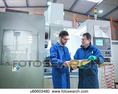 Stock Image - "Workers in discussion next to CNC machine in plastics factory, portrait". Fotosearch