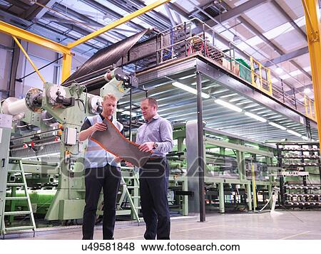 Stock Photo - Workers inspecting carbon fibre sample in carbon fibre factory. Fotosearch