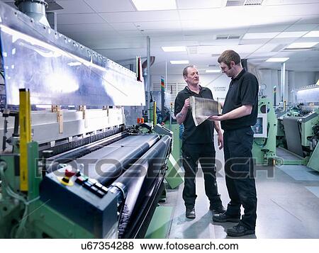 Stock Photo - Workers inspecting carbon fibre sample in carbon fibre factory. Fotosearch