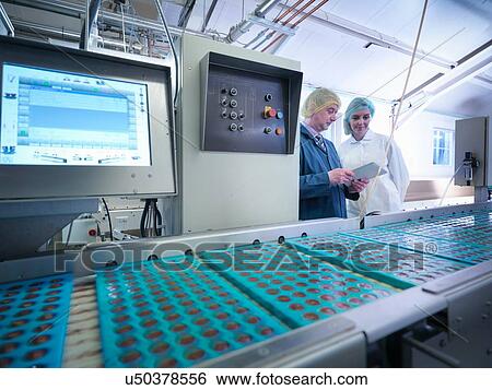Stock Photograph - Workers inspecting chocolates in moulds in chocolate factory. Fotosearch