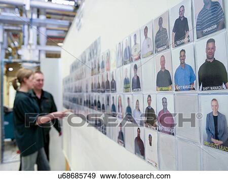 Stock Photo - Workers looking at notice board in factory. Fotosearch