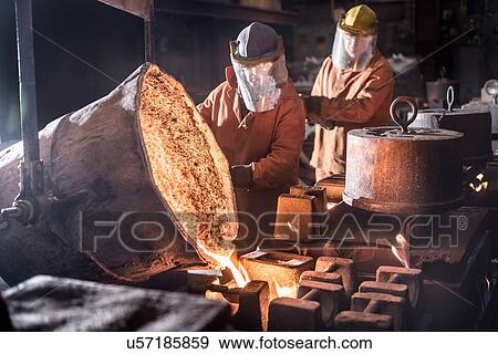 Workers pouring molten metal from flasks into moulds in foundry View Large Photo Image Stock Photo - Workers pouring molten metal from flasks into moulds in foundry. Fotosearch