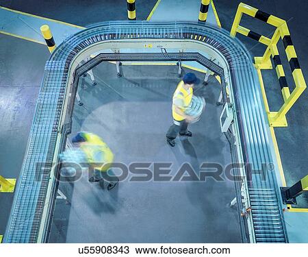 Stock Image - "Workers stacking cans of beer in brewery, high angle view". Fotosearch