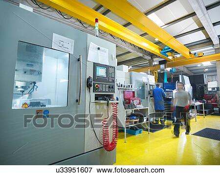Stock Photo - Workers with large CNC machine in plastics factory. Fotosearch