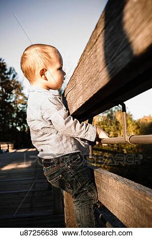 Young boy holding onto wooden gate in rural setting View Large Photo Image Stock Photo - Young boy holding onto wooden gate in rural setting. Fotosearch