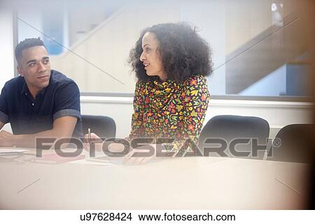 Young businesswoman explaining to team at conference table View Large Photo Image Picture - Young businesswoman explaining to team at conference table. Fotosearch