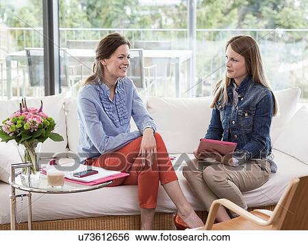 Young businesswoman interviewing mid adult woman on sofa View Large Photo Image Stock Photograph - Young businesswoman interviewing mid adult woman on sofa. Fotosearch