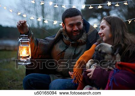 Picture - Young camping couple with dog wrapped in blanket. Fotosearch