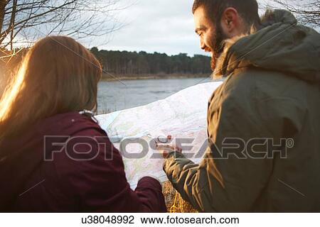 Young couple at lakeside reading map View Large Photo Image Stock Image - Young couple at lakeside reading map. Fotosearch