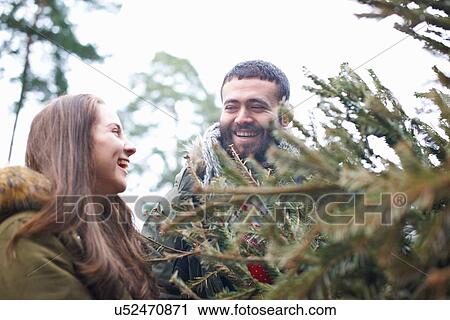 Young couple collecting Christmas tree from forest View Large Photo Image Stock Image - Young couple collecting Christmas tree from forest. Fotosearch