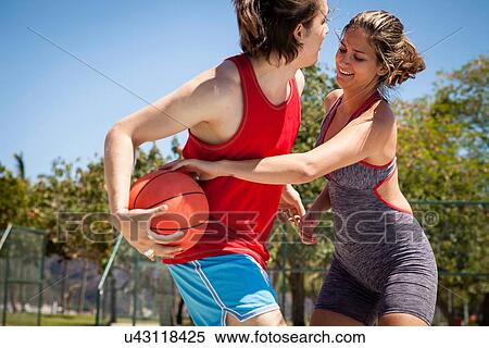 Stock Photography - Young couple flirting on basketball court. Fotosearch