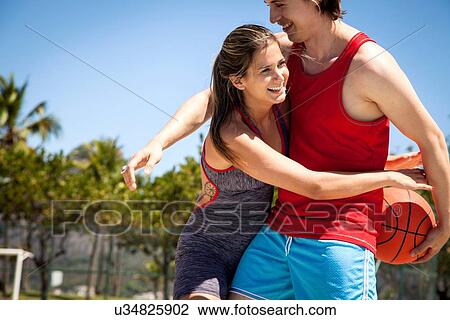 Young couple flirting whilst practicing basketball View Large Photo Image Stock Image - Young couple flirting whilst practicing basketball. Fotosearch