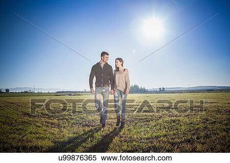 Stock Photography - Young couple holding hands in field. Fotosearch