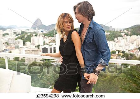 Stock Photo - "Young couple holding hands on rooftop terrace, Rio De Janeiro, Brazil". Fotosearch
