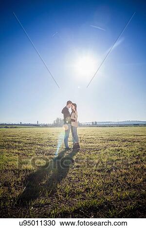 Stock Image - Young couple hugging in field. Fotosearch