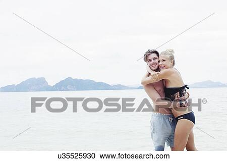Stock Image - "Young couple hugging on beach, Kradan, Thailand". Fotosearch