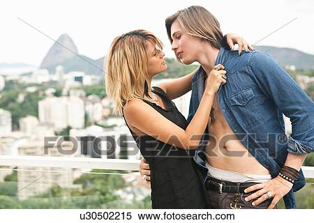 Stock Photography - "Young couple kissing on rooftop terrace, Rio De Janeiro, Brazil". Fotosearch
