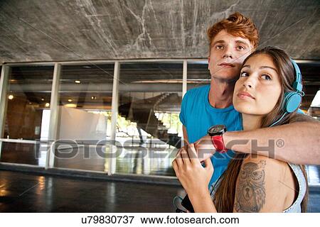 Stock Photo - "Young couple looking away, woman wearing headphones". Fotosearch