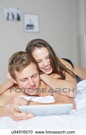 Young couple on bed browsing digital tablet View Large Photo Image Stock Image - Young couple on bed browsing digital tablet. Fotosearch
