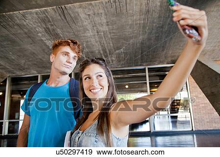 Young couple photographing themselves with phone View Large Photo Image Stock Photo - Young couple photographing themselves with phone. Fotosearch