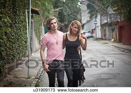 Young couple strolling along suburban street View Large Photo Image Stock Image - Young couple strolling along suburban street. Fotosearch