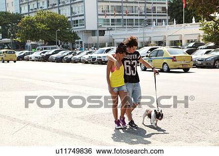 Stock Photograph - "Young couple strolling with dog along sidewalk, Copacabana, Rio De Janeiro, Brazil". Fotosearch