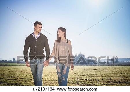 Young couple walking in field View Large Photo Image Picture - Young couple walking in field. Fotosearch