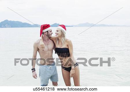 Stock Photo - "Young couple wearing santa hats on beach, Kradan, Thailand". Fotosearch