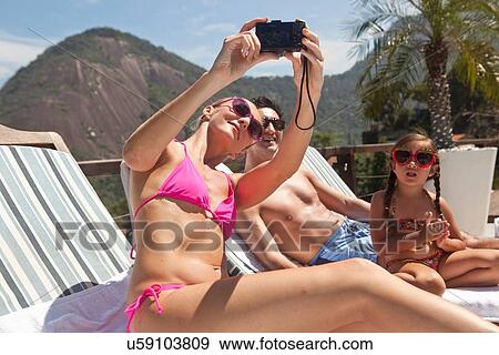 "Young family on sun loungers, mother taking self portrait of family" View Large Photo Image Stock Photo - "Young family on sun loungers, mother taking self portrait of family". Fotosearch