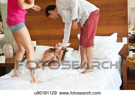 Stock Photo - Young family playing on bed. Fotosearch