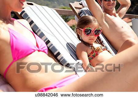 "Young family relaxing on sun loungers, low angle view" View Large Photo Image Stock Photograph - "Young family relaxing on sun loungers, low angle view". Fotosearch