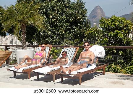 Stock Image - "Young family sunbathing by pool, Rio de Janeiro, Brazil". Fotosearch