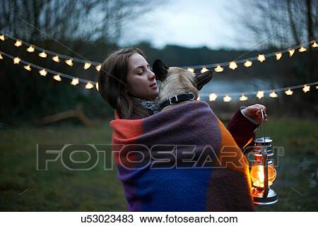 Stock Image - Young female camper with dog wrapped in blanket. Fotosearch
