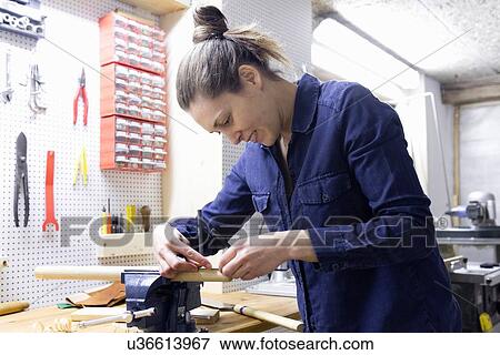 Young female carpenter measuring timber in workshop vice View Large Photo Image Stock Photo - Young female carpenter measuring timber in workshop vice. Fotosearch