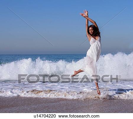 Young female dancer leaping mid air in ocean waves View Large Photo Image Stock Image - Young female dancer leaping mid air in ocean waves. Fotosearch