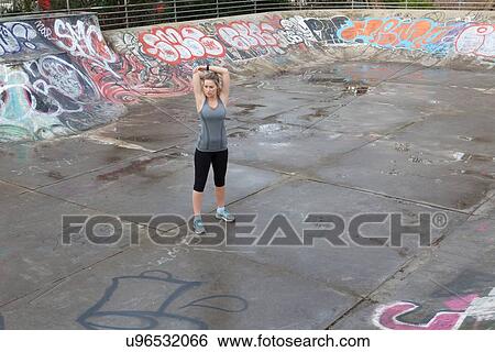 Young female runner warming up in skatepark View Large Photo Image Stock Photograph - Young female runner warming up in skatepark. Fotosearch